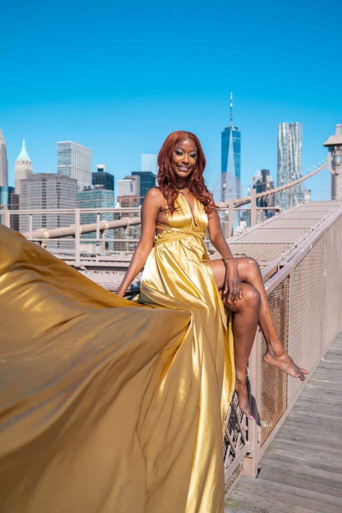 woman in a gold dress at the Brooklyn Bridge doing a flying dress photoshoot with Flying Dresses New York